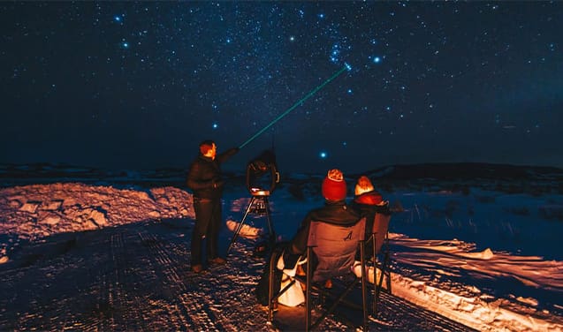 A group of people sitting on top of a snowy slope.