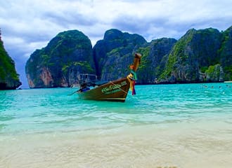 A boat floating on top of the water near some mountains.