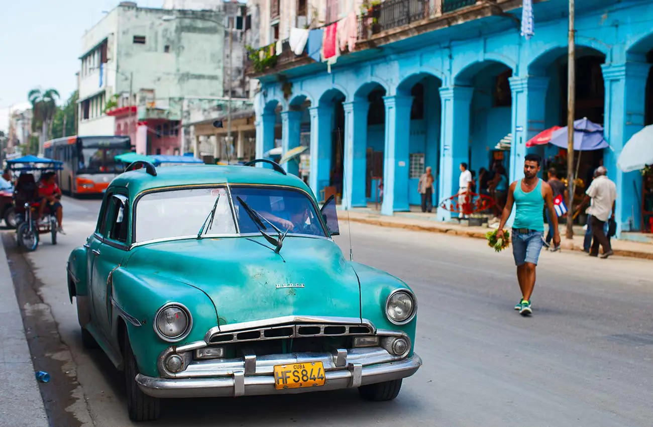 A blue car is parked on the side of the road.