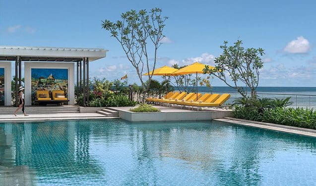 A pool with yellow chairs and an umbrella.