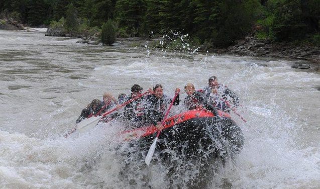 A group of people are in the water on a raft.