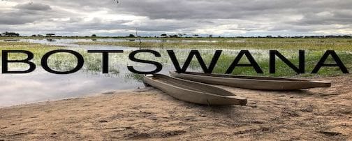 A boat on the beach with water and clouds in background.