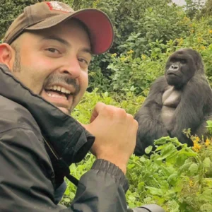 A man in a hat and jacket standing next to two gorillas.