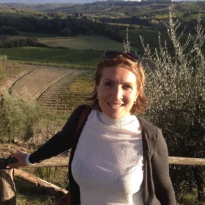 A woman standing on top of a hill near some trees.