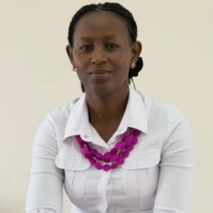 A woman wearing a white shirt and pink necklace.