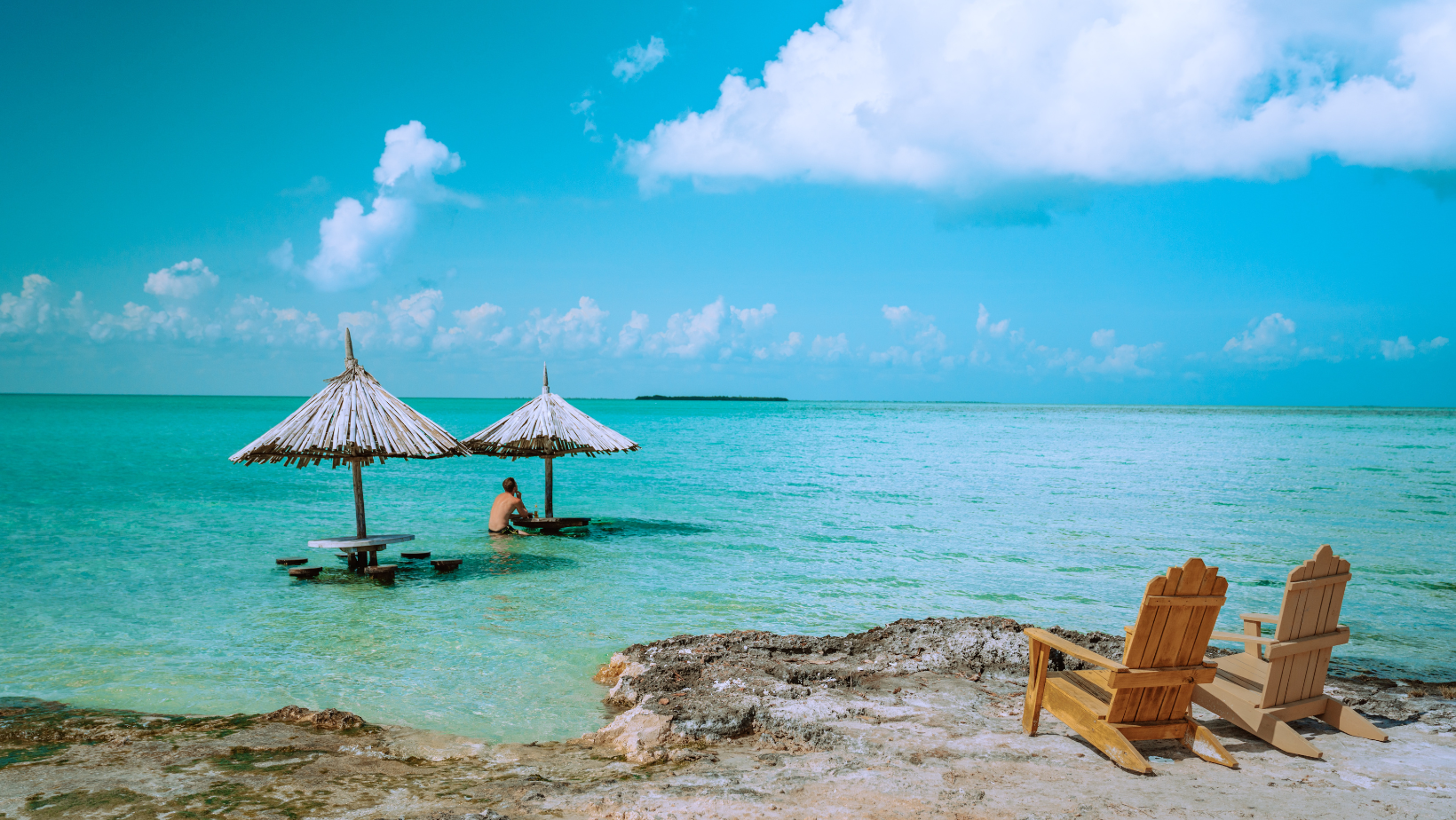 A person sitting on the beach under an umbrella.