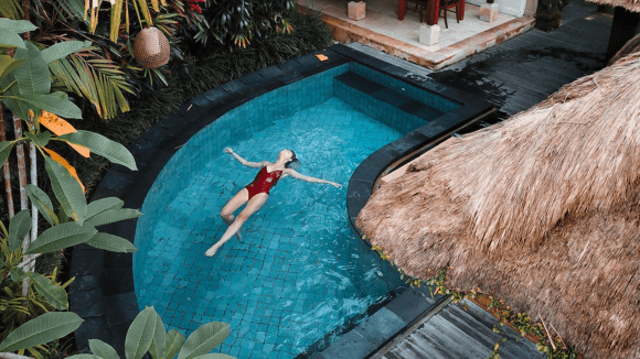 A woman in red bathing suit floating on top of pool.