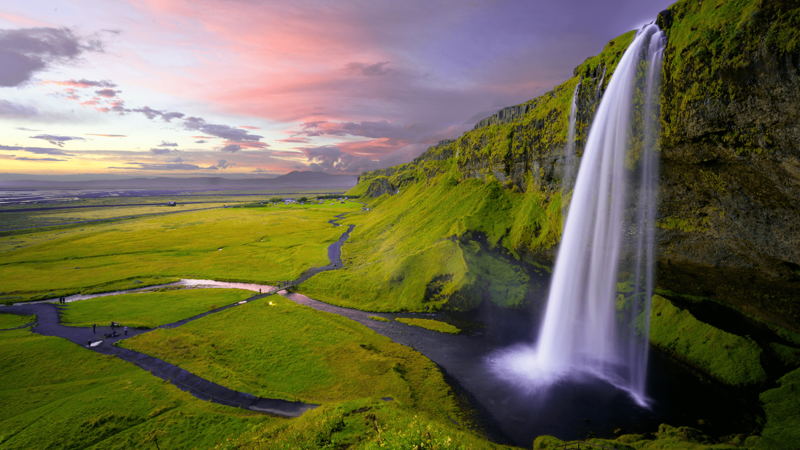 A waterfall is shown in the middle of a green valley.