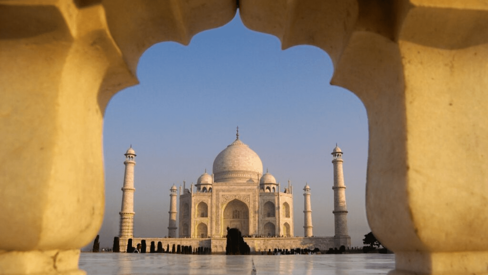 A view of the taj mahal from inside an archway.