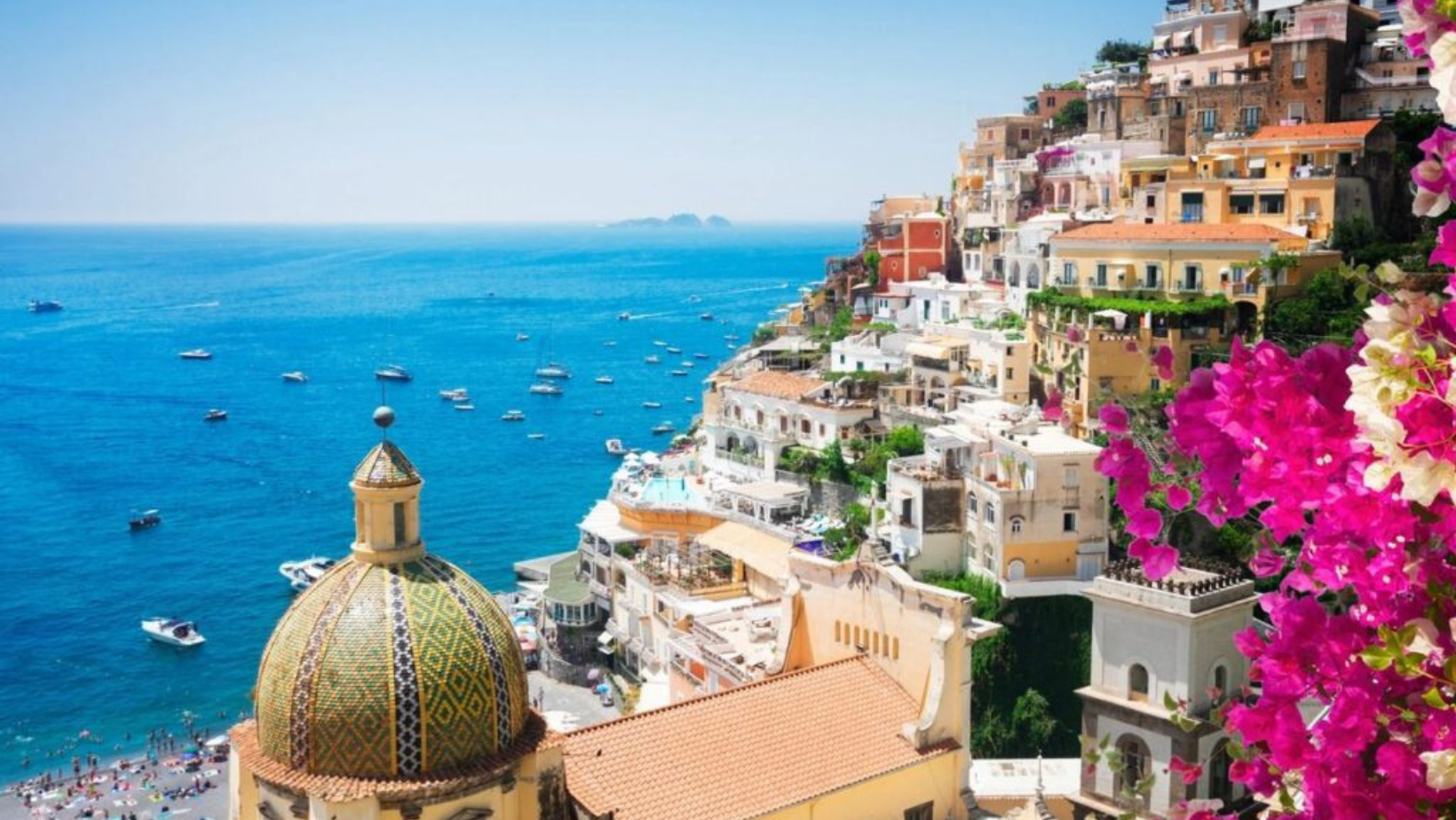 A view of the ocean and buildings on top of a hill.