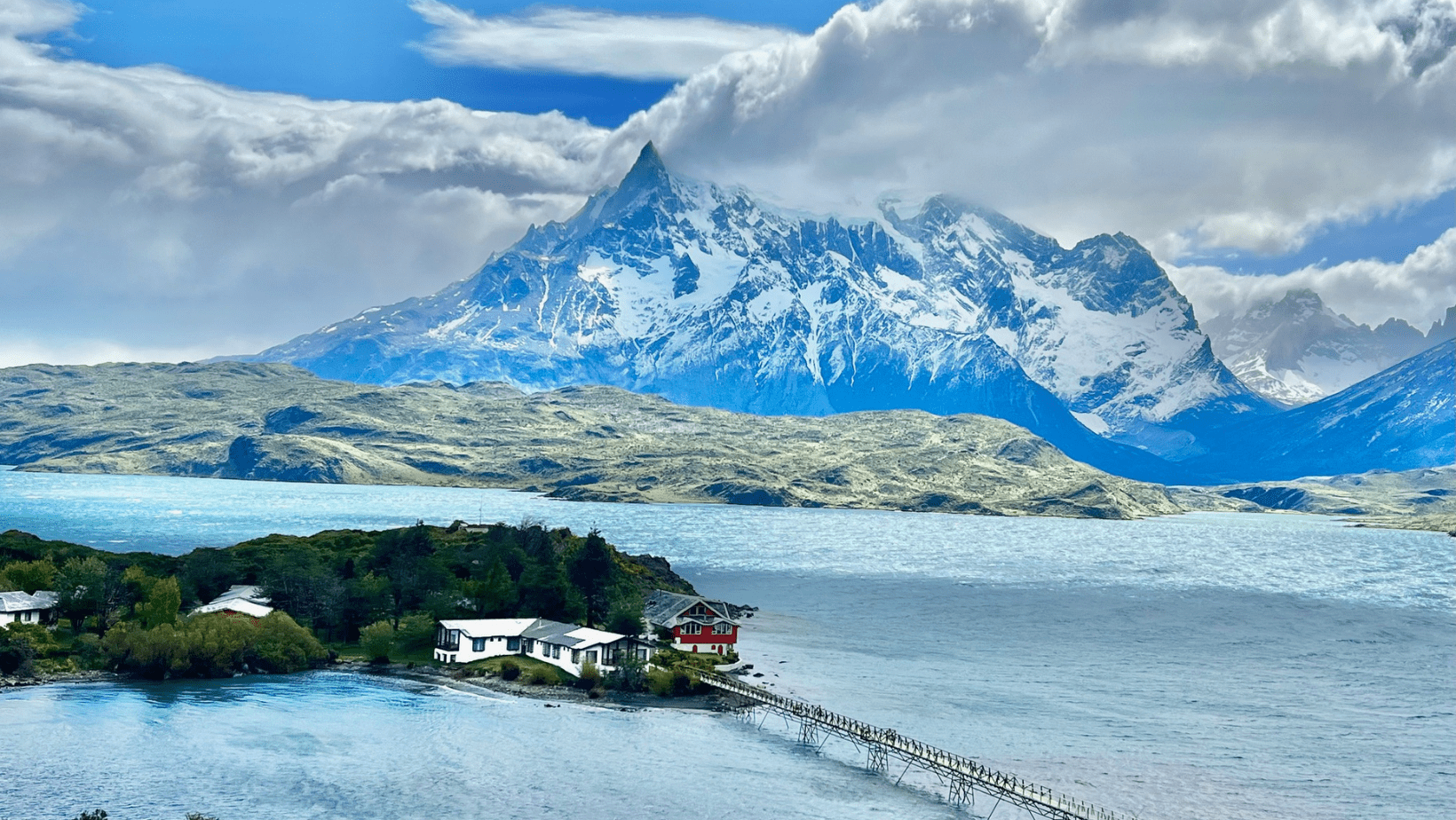 A small island in the middle of a lake with mountains behind it.