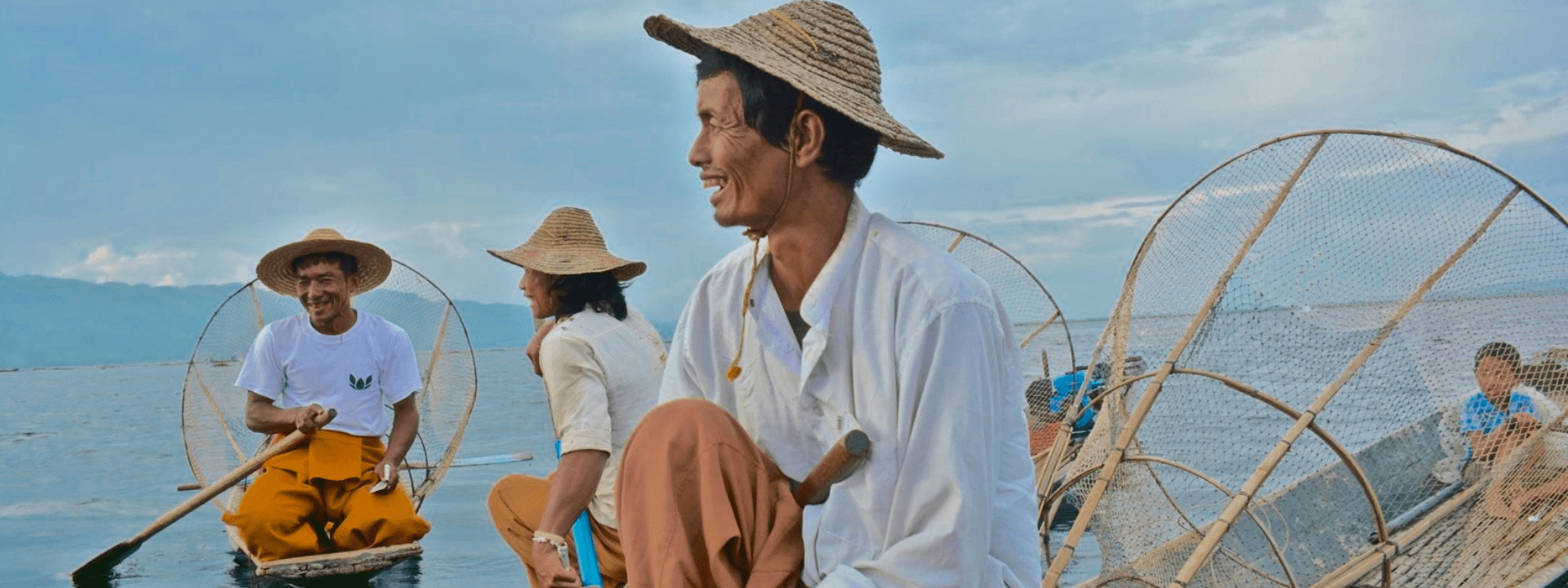 A man sitting on the beach wearing a hat.